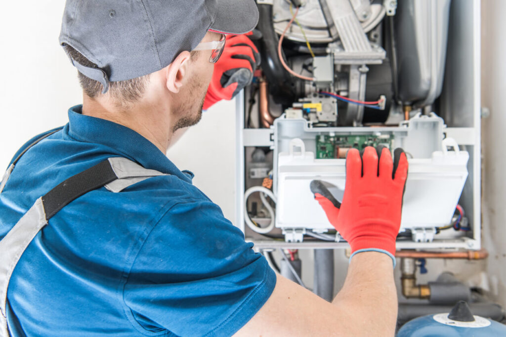A repair technician inspecting a central gas furnace.