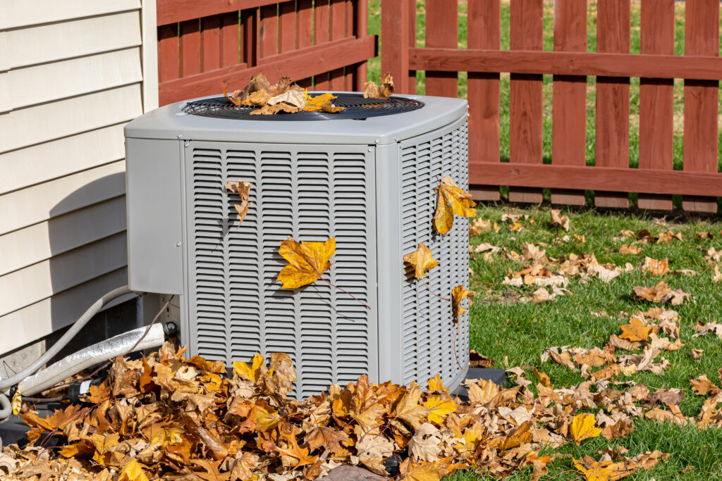 Air conditioning unit covered in orange and brown fall leaves