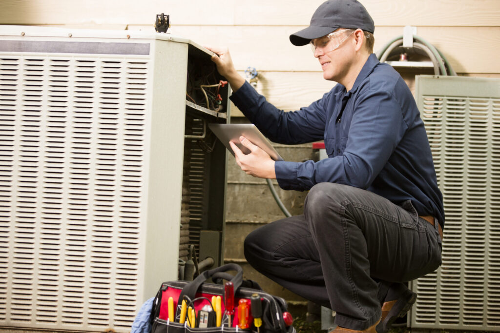 Repairmen works on a home's air conditioner unit outdoors.
