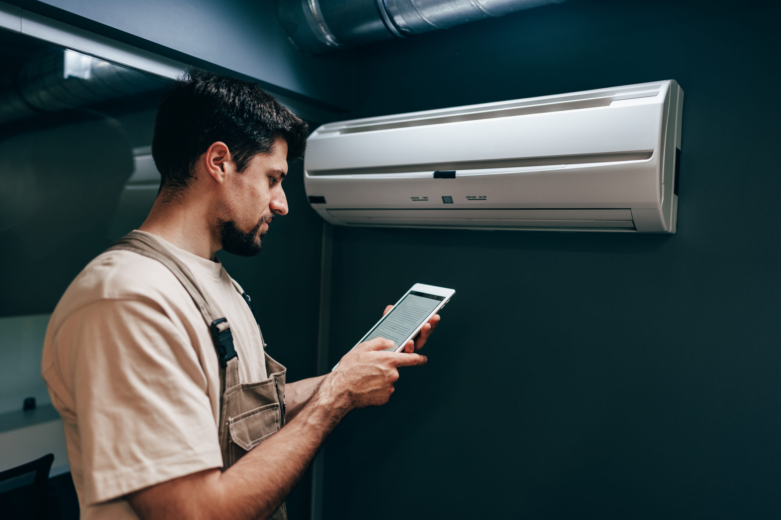 A technician stands close to an air conditioning unit,